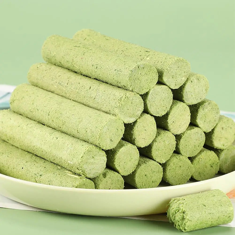 Green pet treats stacked on a white plate with a green background